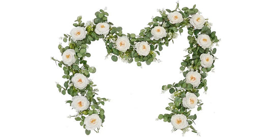 Elegant artificial eucalyptus garland decorated with white cream roses and small flowers on white background