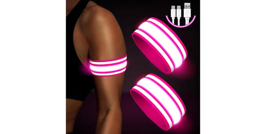 Person wearing bright pink LED armband on upper arm for night safety running with USB charging cable